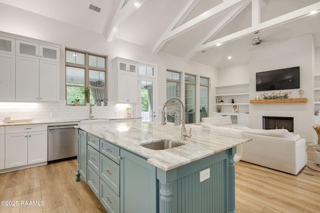 137 Grandview Terrace Dr, Youngsville, LA 70592 - kitchen with stainless steel dishwasher, a sink, white cabinetry, open floor plan, and beam ceiling