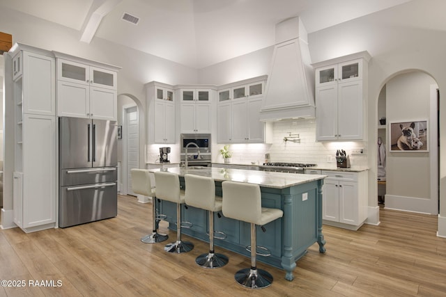 137 Grandview Terrace Dr, Youngsville, LA 70592 - kitchen with stainless steel appliances, custom exhaust hood, arched walkways, white cabinetry, and high vaulted ceiling