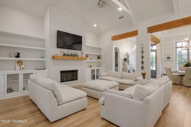 137 Grandview Terrace Dr, Youngsville, LA 70592 - living room with built in shelves, beam ceiling, light wood-style floors, a brick fireplace, and a high ceiling