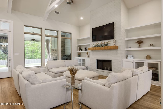 137 Grandview Terrace Dr, Youngsville, LA 70592 - living area with ceiling fan, built in shelves, a brick fireplace, wood finished floors, and beamed ceiling