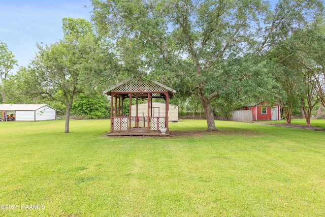 view of grassy yard featuring a gazebo, a shed, an outbuilding, and view of scattered trees