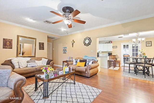 living room with a ceiling fan, light wood-type flooring, crown molding, a chandelier, and baseboards