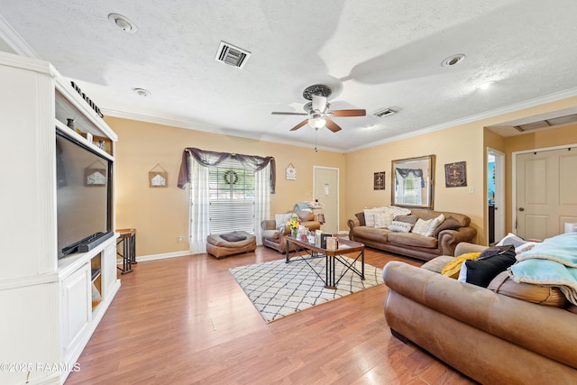 living room featuring light wood-type flooring, a textured ceiling, ceiling fan, crown molding, and baseboards