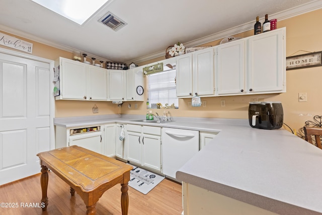 kitchen with white dishwasher, crown molding, light countertops, white cabinetry, and light wood-type flooring