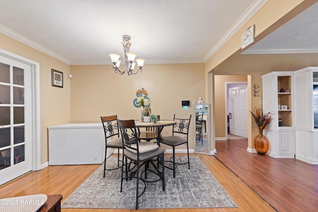 dining area with light wood-style floors, ornamental molding, a chandelier, and baseboards