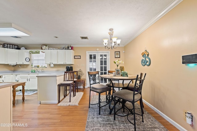 dining area featuring light wood-style floors, a chandelier, crown molding, and baseboards