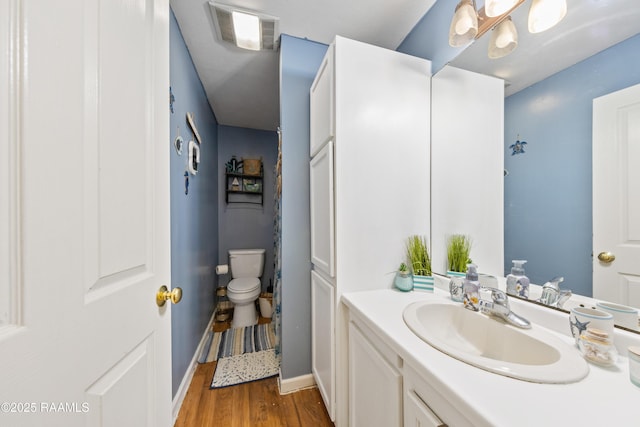 bathroom featuring wood finished floors, toilet, vanity, and baseboards