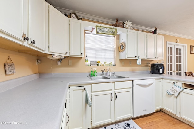 kitchen with dishwasher, a sink, light countertops, white cabinets, and ornamental molding