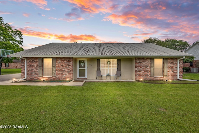 view of front of home featuring a lawn, covered porch, brick siding, and stucco siding