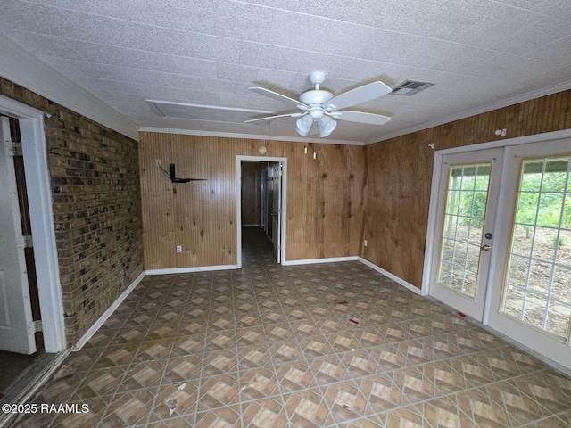unfurnished room featuring wood walls, baseboards, a ceiling fan, french doors, and ornamental molding