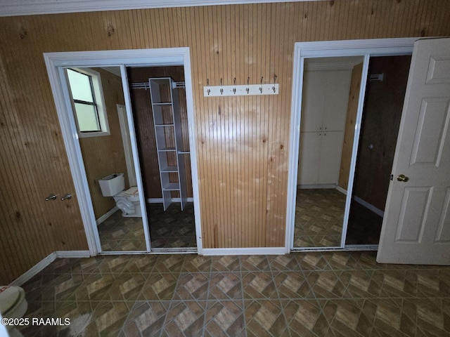 unfurnished bedroom with tile patterned floors, baseboards, and wooden walls