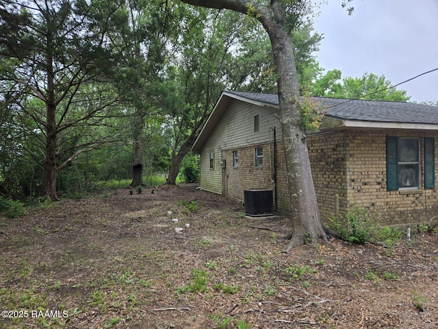 view of property exterior with central AC unit and brick siding