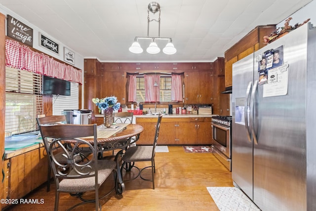 408 Loraine St, Abbeville, LA 70510 - kitchen with stainless steel appliances, light countertops, light wood finished floors, brown cabinets, and pendant lighting