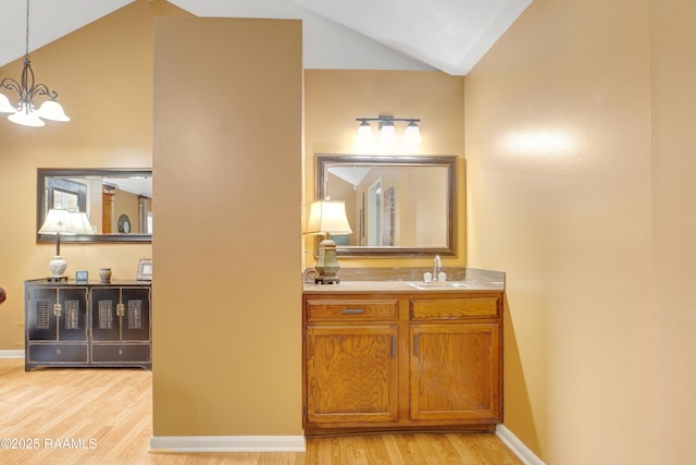 116 Twin Lakes Dr, Youngsville, LA 70592 - bathroom with lofted ceiling, wood finished floors, a chandelier, vanity, and baseboards