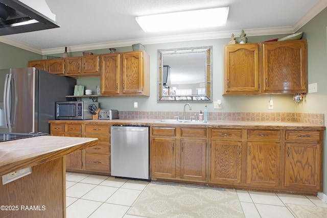 116 Twin Lakes Dr, Youngsville, LA 70592 - kitchen featuring appliances with stainless steel finishes, a sink, crown molding, light tile patterned flooring, and brown cabinets