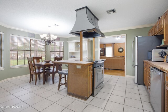 116 Twin Lakes Dr, Youngsville, LA 70592 - kitchen with appliances with stainless steel finishes, island exhaust hood, crown molding, a chandelier, and light tile patterned flooring