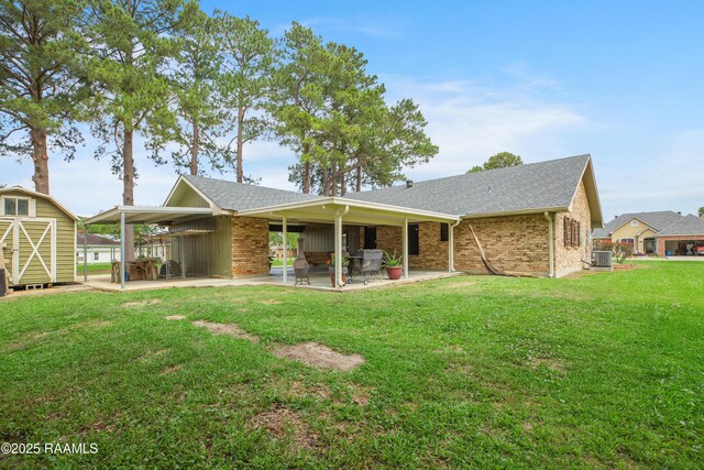 116 Twin Lakes Dr, Youngsville, LA 70592 - rear view of house with a storage unit, an outbuilding, brick siding, cooling unit, and roof with shingles