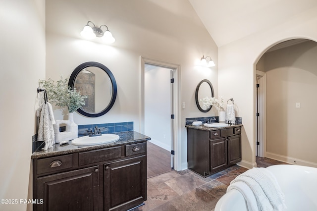 112 Heathwood Dr, Broussard, LA 70518 - full bathroom featuring vaulted ceiling, two vanities, a bathtub, baseboards, and stone finish floors