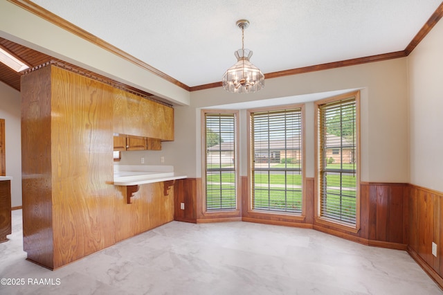 505 River Woods Dr, Lafayette, LA 70508 - kitchen with wainscoting, wood walls, a chandelier, crown molding, and brown cabinetry