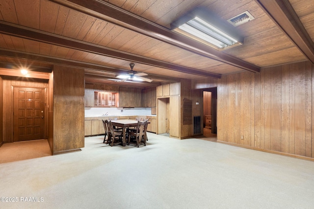 1341 College Rd, Eunice, LA 70535 - dining space with wood ceiling, beam ceiling, light colored carpet, wood walls, and a ceiling fan