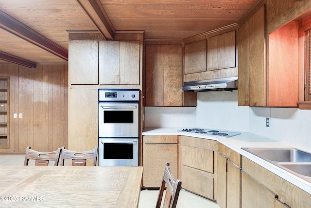 1341 College Rd, Eunice, LA 70535 - kitchen featuring multiple ovens, wood ceiling, under cabinet range hood, light countertops, and wood walls