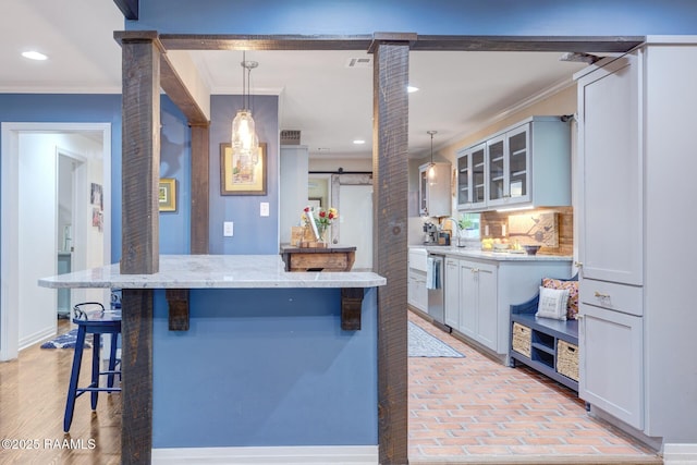 209 Irene Cir, Lafayette, LA 70503 - kitchen featuring ornamental molding, a kitchen bar, glass insert cabinets, dishwasher, and hanging light fixtures