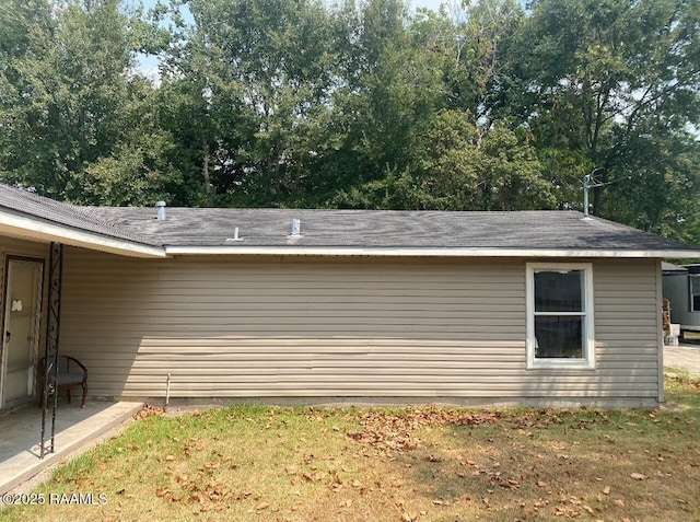 view of home's exterior featuring roof with shingles and view of wooded area