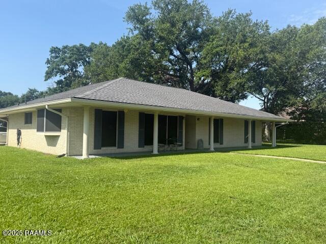 back of property featuring a lawn and brick siding