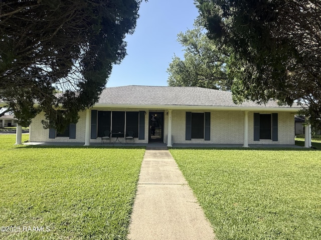 ranch-style home featuring brick siding, a front lawn, and roof with shingles
