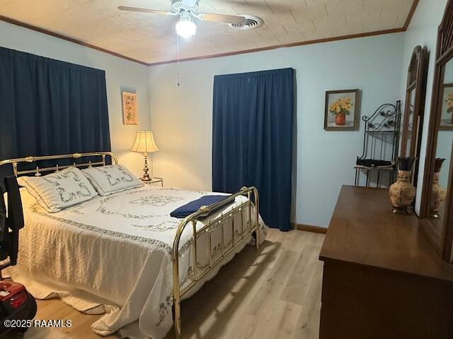bedroom featuring wood finished floors, ornamental molding, and ceiling fan