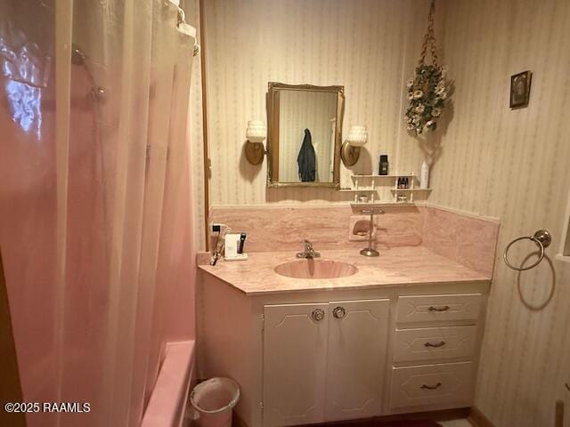 full bath with vanity, wallpapered walls, and shower / tub combo with curtain