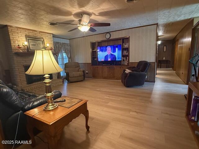 living room featuring a ceiling fan, wood finished floors, and wooden walls