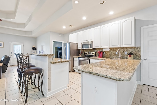 201 Rue Paon, Youngsville, LA 70592 - kitchen with appliances with stainless steel finishes, a breakfast bar, a sink, light tile patterned flooring, and tasteful backsplash