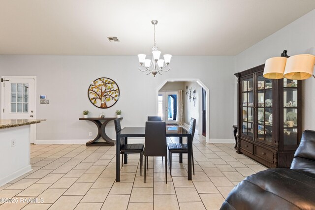 201 Rue Paon, Youngsville, LA 70592 - dining area with a chandelier, light tile patterned floors, arched walkways, and baseboards