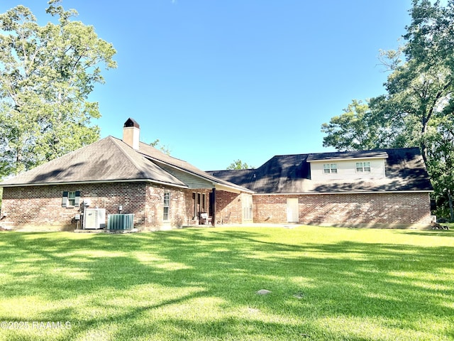 277 Carrera Ln, Eunice, LA 70535 - back of property featuring brick siding, a yard, central AC unit, and a chimney