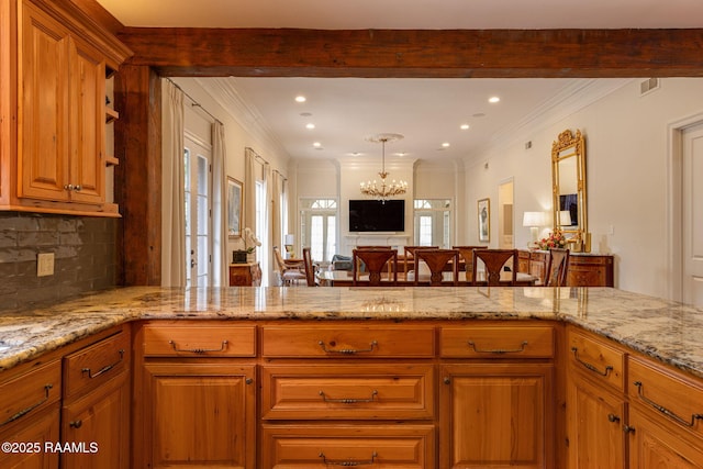315 Kings Rd, Lafayette, LA 70503 - kitchen with light stone countertops, decorative backsplash, open floor plan, a chandelier, and brown cabinets