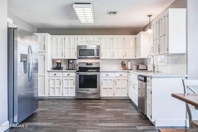 109 Bellevedere Ave, Lafayette, LA 70503 - kitchen with appliances with stainless steel finishes, a sink, white cabinets, dark wood finished floors, and a textured ceiling