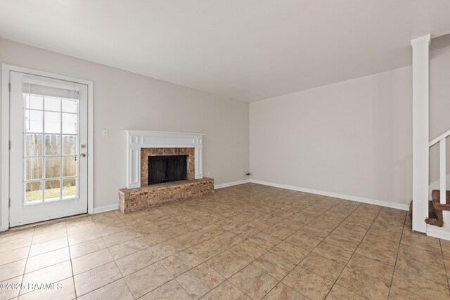 116 Southfield Pkwy, Lafayette, LA 70506 - unfurnished living room featuring stairs, a fireplace, plenty of natural light, and light tile patterned floors