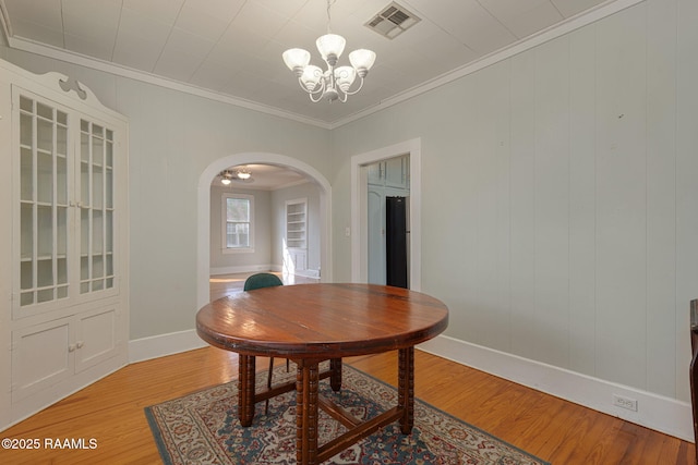 308 Boas Ave, New Iberia, LA 70563 - dining area with arched walkways, a chandelier, baseboards, light wood-type flooring, and ornamental molding