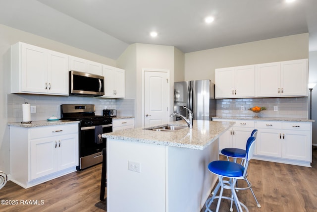 7014 Acacia Lake Dr, Maurice, LA 70555 - kitchen with appliances with stainless steel finishes, a sink, a breakfast bar, backsplash, and wood finished floors