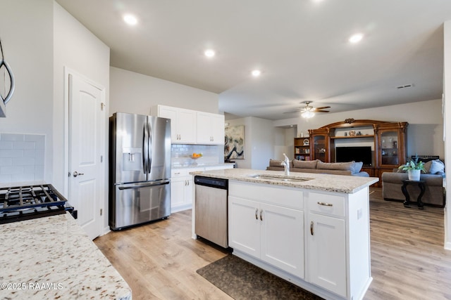 7014 Acacia Lake Dr, Maurice, LA 70555 - kitchen featuring appliances with stainless steel finishes, a sink, light wood-type flooring, decorative backsplash, and white cabinets