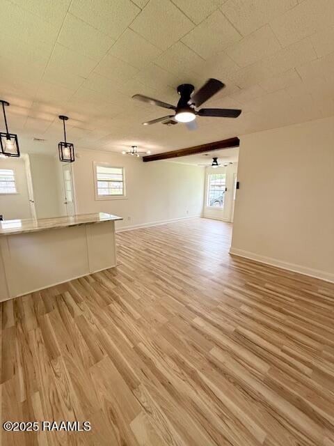 unfurnished living room featuring a ceiling fan, light wood finished floors, and baseboards