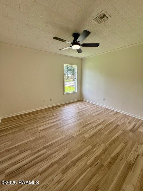 empty room featuring light wood-style floors, a ceiling fan, and baseboards