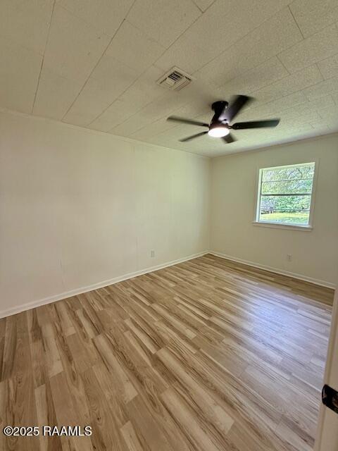 unfurnished room featuring ceiling fan, wood finished floors, and baseboards