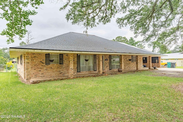 1005 Tensas Dr, Opelousas, LA 70570 - back of house featuring roof with shingles, a yard, and brick siding