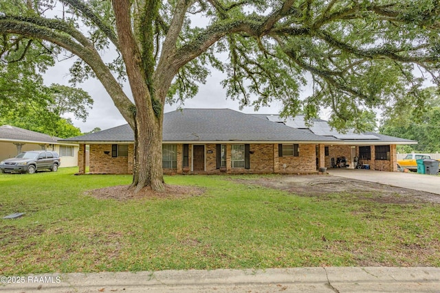 1005 Tensas Dr, Opelousas, LA 70570 - ranch-style house featuring driveway, roof mounted solar panels, a front yard, a carport, and brick siding