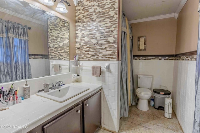 1005 Tensas Dr, Opelousas, LA 70570 - bathroom featuring speckled floor, crown molding, tile walls, wainscoting, and toilet