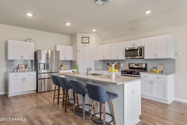 110 Casa Bella Ct, Breaux Bridge, LA 70517 - kitchen featuring stainless steel appliances, decorative backsplash, a kitchen bar, white cabinets, and an island with sink