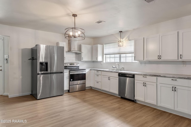 164 Mimosa Pl, Lafayette, LA 70506 - kitchen featuring stainless steel appliances, wall chimney range hood, decorative backsplash, light wood-type flooring, and white cabinetry