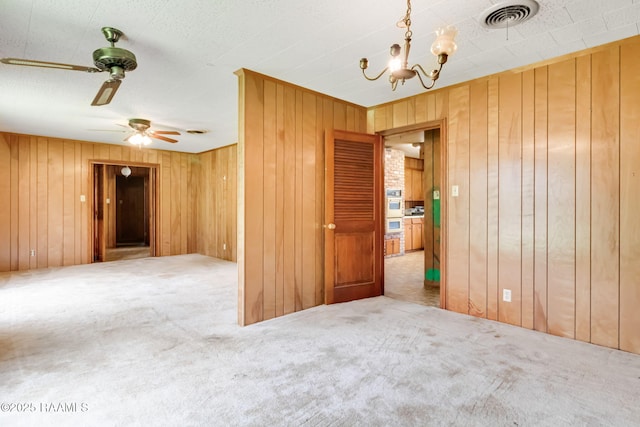 506 Rice Ln, Opelousas, LA 70570 - carpeted empty room featuring a chandelier, wooden walls, and a ceiling fan